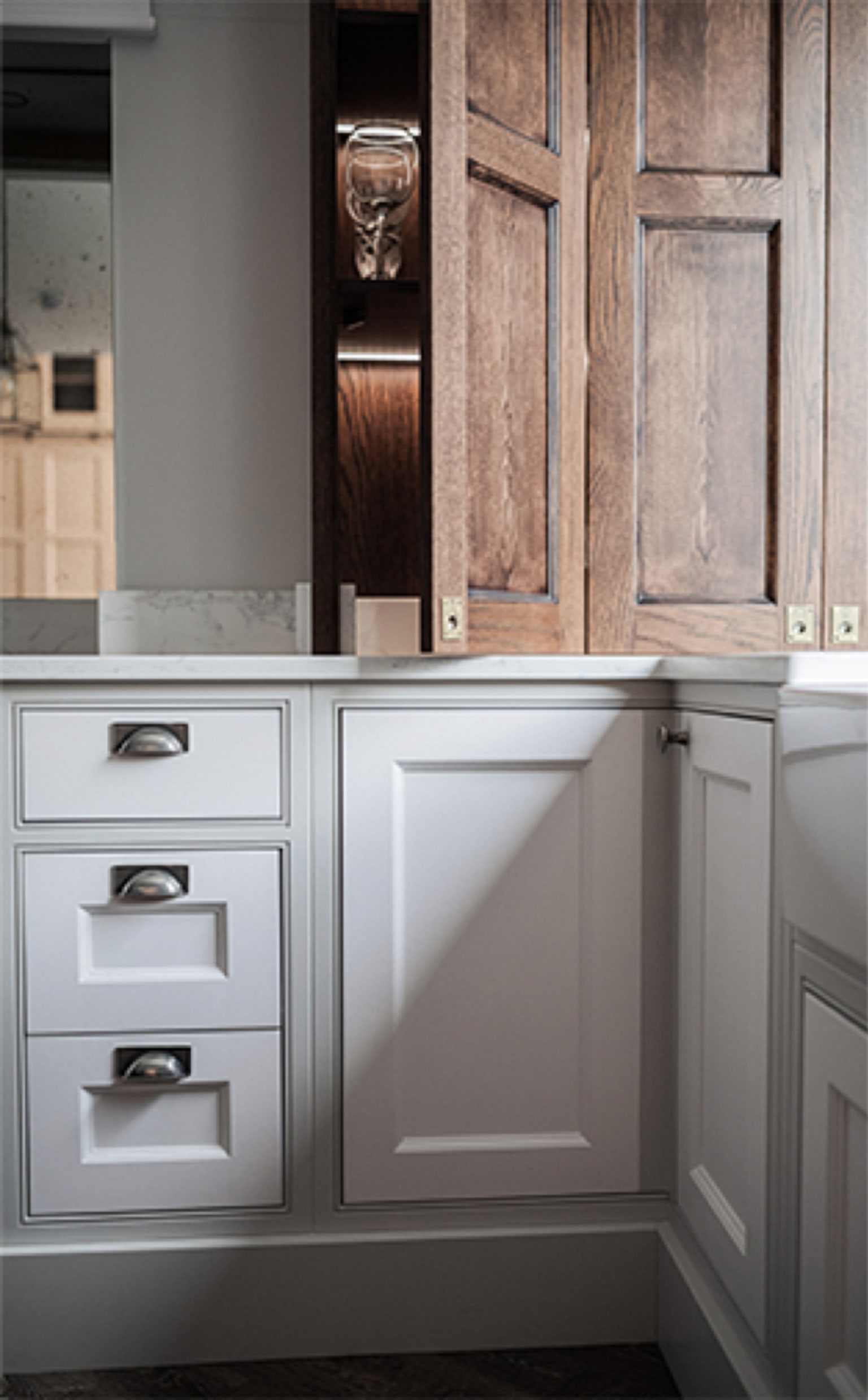 Fumed-oak in-frame upper cabinet beside an off-white painted base with chrome cup handles, in the Turner Street showroom